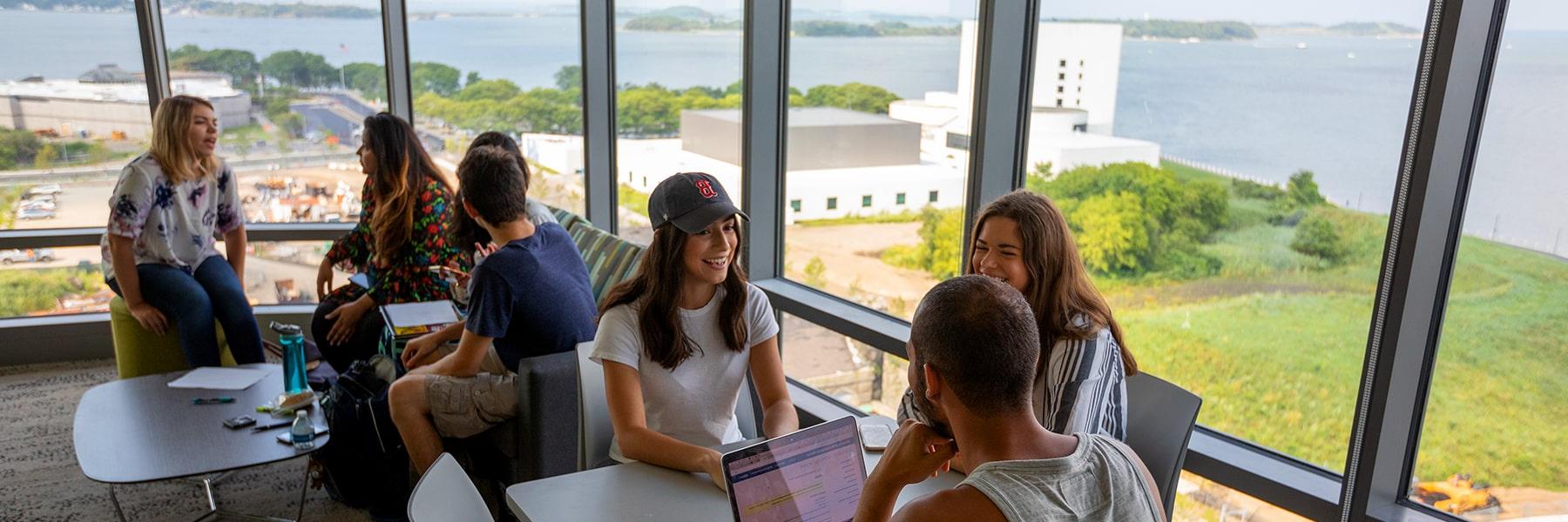 Students in Residence Hall Lounge with view of the water.